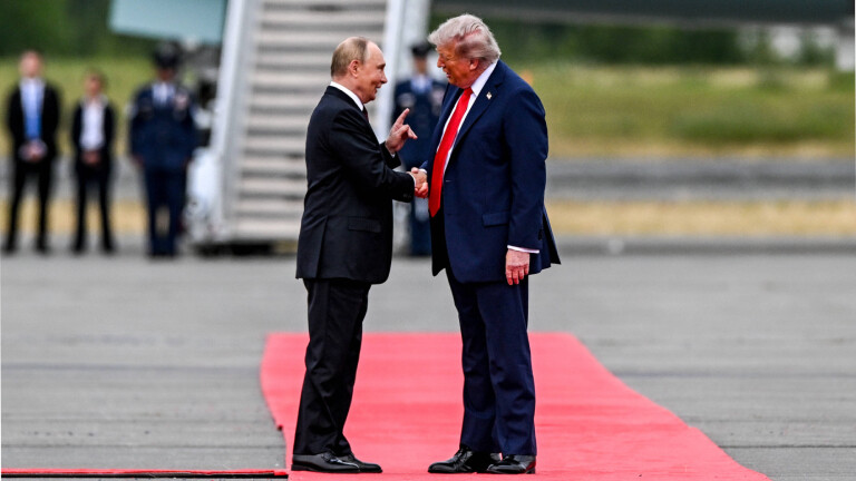 Wladimir Putin und Donald Trump auf einem roten Teppich auf einem Rollfeld in Alaska