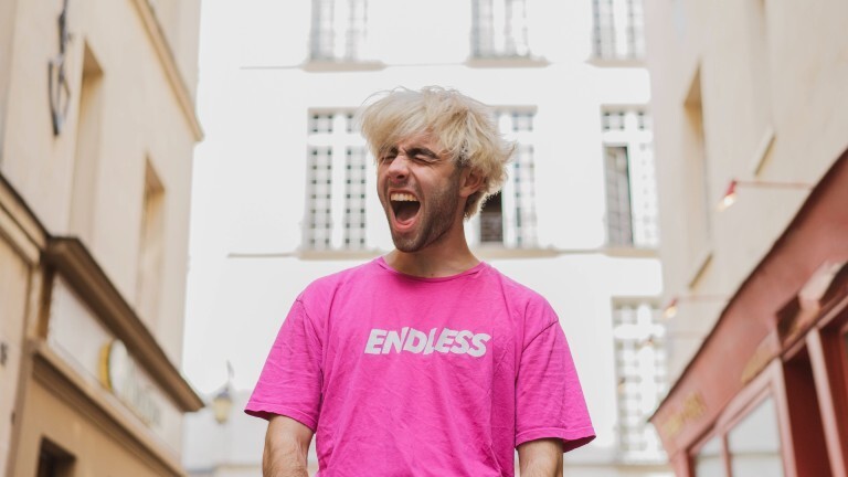 Ein blonder Jugendlicher mit einem pinknen T-Shirt schreit.