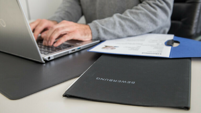 Ein Mann schaut sich in einem Büro Bewerbungsunterlagen an.