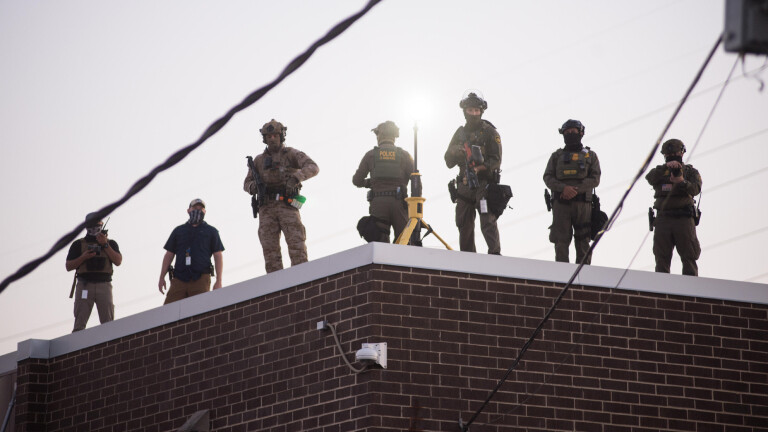 Bewaffnete, vermummte Männer stehen auf einem Dach.