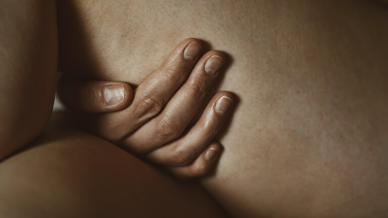 Nahaufnahme einer Hand, die sinnlich und intim ein Bein berührt