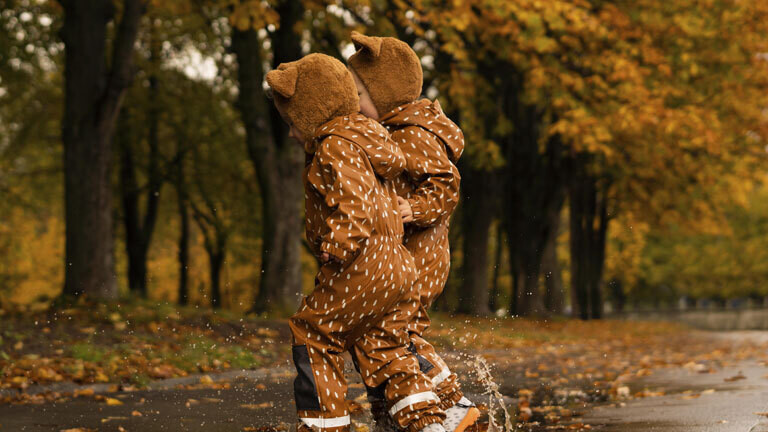 Kleine Geschwisterkinder spielen zusammen im Herbst