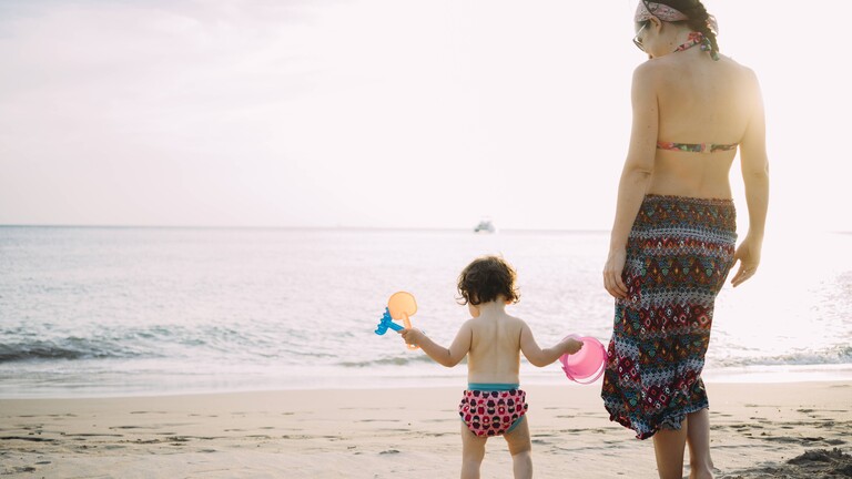 Foto einer jungen Mutter mit Kleinkind am Strand