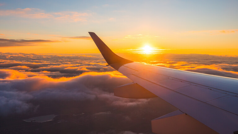 Ein Flugzeug fliegt bei Sonnenuntergang