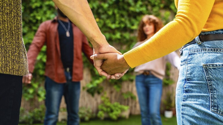 Verschiedene Menschen bilden einen Kreis und halten sich an den Händen .