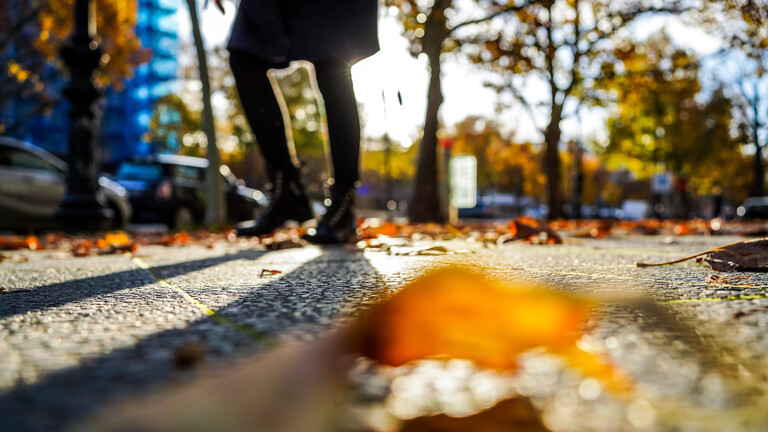 Eine Frau läuft durch Berlin, am Boden liegt ein Laubblatt