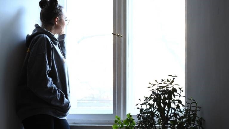 Eine Frau schaut nachdenklich aus dem Fenster