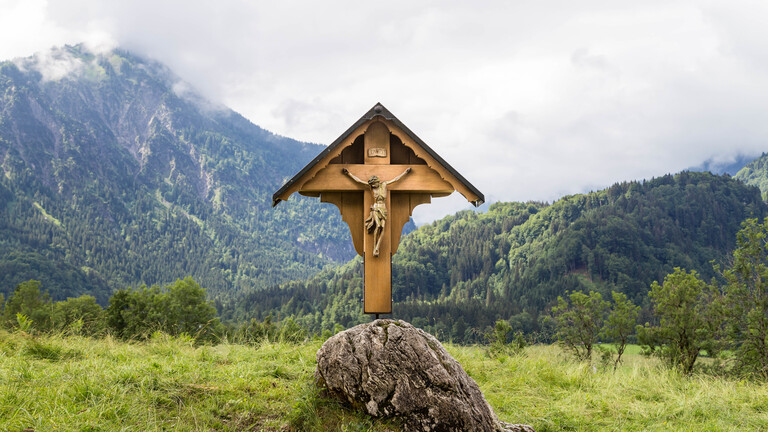 Ein Wegekreuz vor Bergkulisse