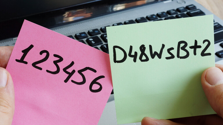 Zwei Passwörter auf Post-its, ein Laptop im Hintergrund.