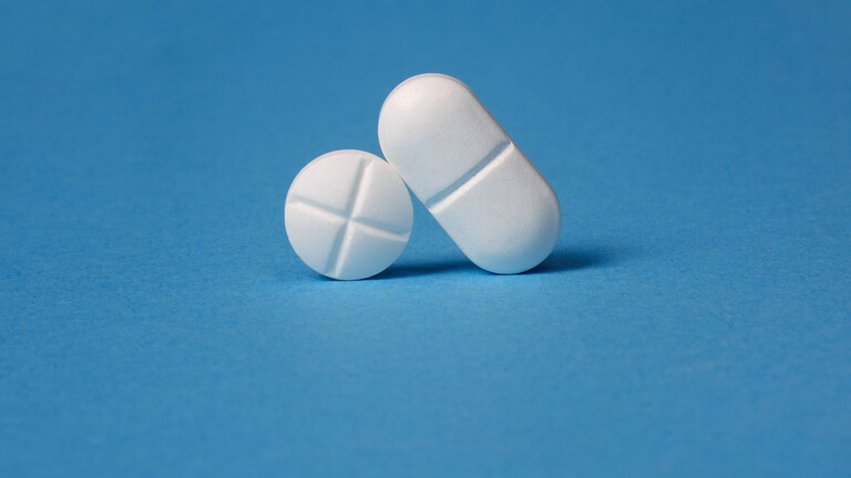 Vor einem blauen Hintergrund sind zwei Tabletten aufgestellt. Eine ist rund und die andere Tablette ist oval.