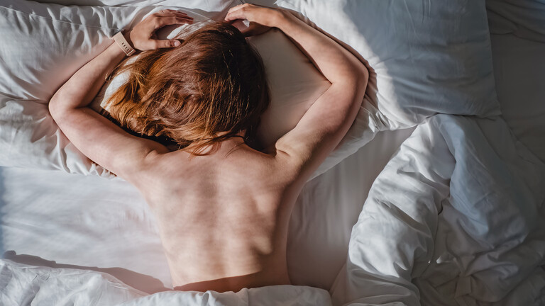 Eine Frau liegt bäuchlings in ihrem Bett