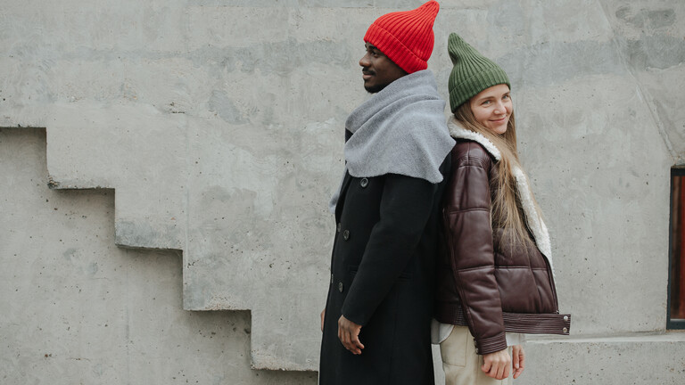 Ein Mann und eine Frau stehen Rücken an Rücken an einer Betonwand