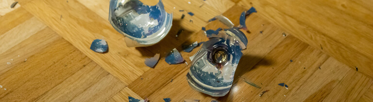 Auf dem Parkettboden liegt eine zerbrochene Christbaumkugel.