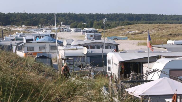 Auf einem Campingplatz in Prerow sieht man mehrere Campingwagen in einer Dünenlandschaft.