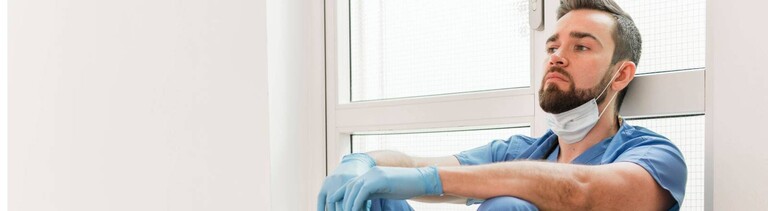 Krankenpfleger sitzt erschöpft auf dem Boden