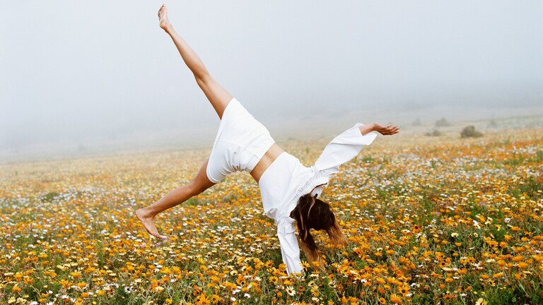 Eine Frau schlägt ein Rad auf einer Wiese