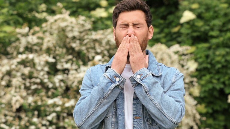 Mann im Freien muss niesen (Symbolfoto).