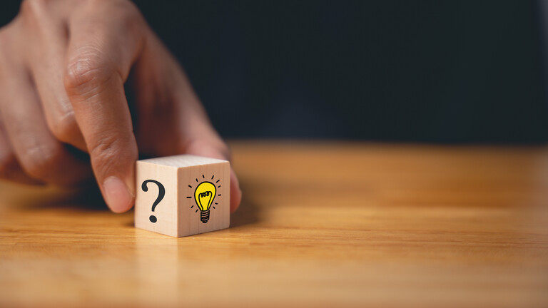 Ein Würfel mit einem Fragezeichen und einer Glühbirne