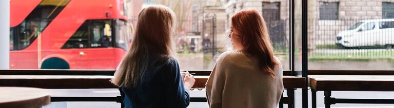 Zwei Frauen sitzen in einem Café nebeneinander