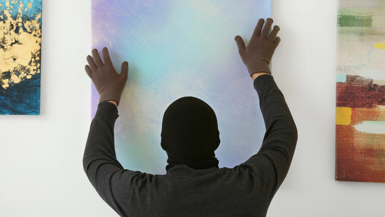 Ein Mann nimmt ein Gemälde von der Wand in einer Galerie