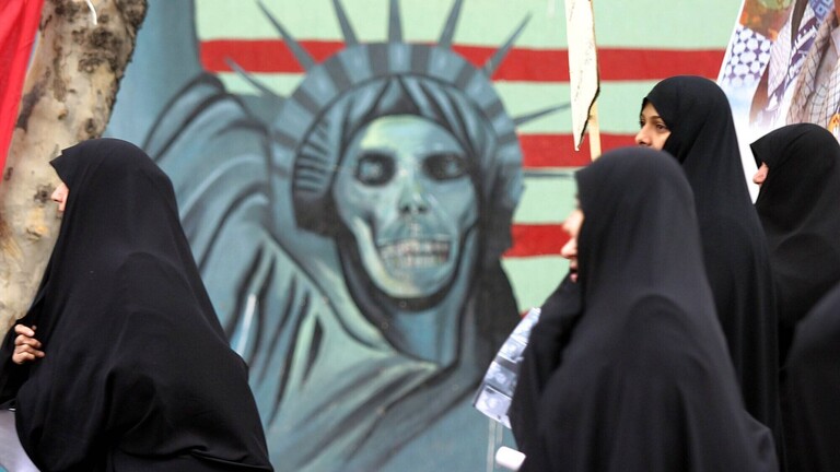 Weibliche Demonstranten vor einem leichenhaften Freiheitsstatuen-Graffiti während einer anti-amerikanischen Demonstration in Teheran -