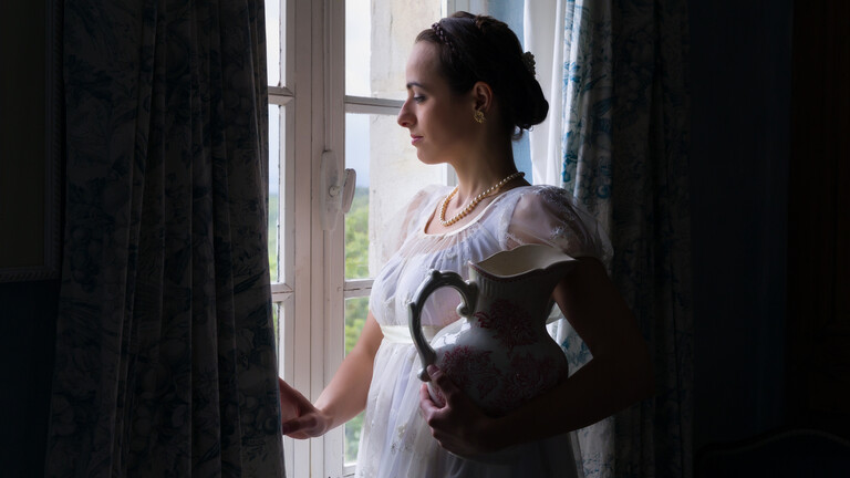 Eine Frau, die im Stil des frühen 19. Jahrhunderts angezogen und gestylt ist.