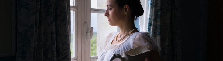 Eine Frau, die im Stil des frühen 19. Jahrhunderts angezogen und gestylt ist.