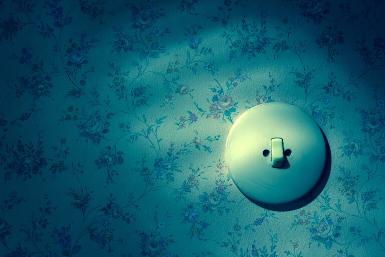 Eine alte Tapete mit Lichtschalter. Symbolfoto fuer Erneuerung und renovieren.