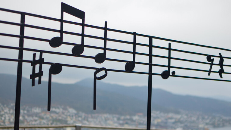 Musikalische Noten im Kontrast zur Landschaft von Bergen auf dem Berg Fløyen in Norwegen.