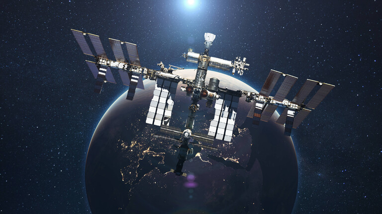 Die ISS fliegt vor dem Hintergrund des blauen Planeten Erde mit dem Licht der Sonne.