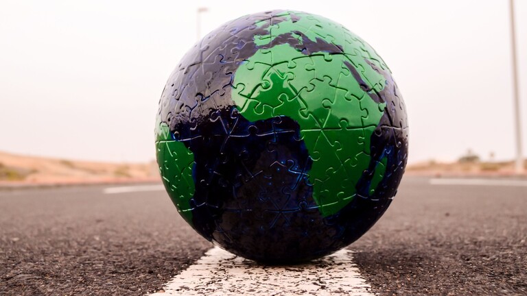 Ein schwarzer Globus mit grün eingefärbten Kontinenten auf einer Asphaltstraße