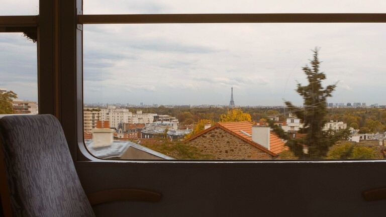 Aus einem Zugfenster sieht man in der Ferne den Eiffelturm.