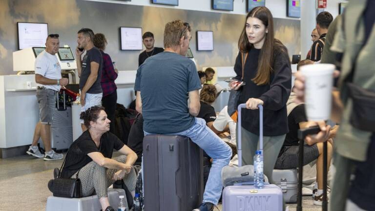 Passagiere sitzen und stehen mit ihren Koffern am Flughafen