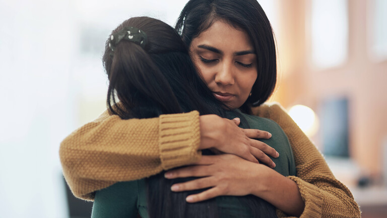 Eine Frau umarmt eine andere innig, ihre Augen sind geschlossen, Freundschaft, Anteilnahme, Nähe