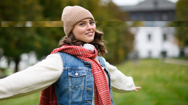 Eine Frau mit Mütze springt über eine Wiese. ihre Augenpartie ist übercollagiert