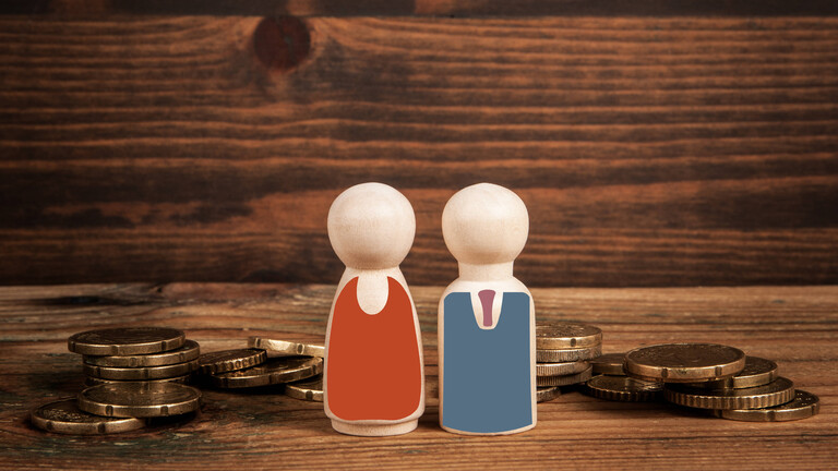 Zwei Holzfiguren stehen auf Holz inmitten von Kleingeld