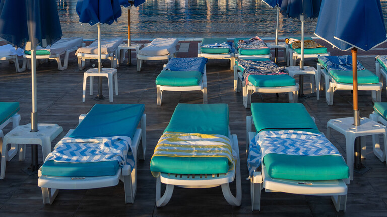 Mit Handtüchern sind alle Liegen an einem Hotelpool in Malia auf der Insel Kreta reserviert.