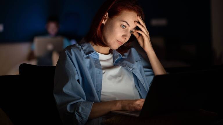 Eine Frau sitzt abends vor dem Laptop