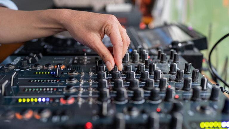 Eine DJ regelt den Ton an einem Mischpult.