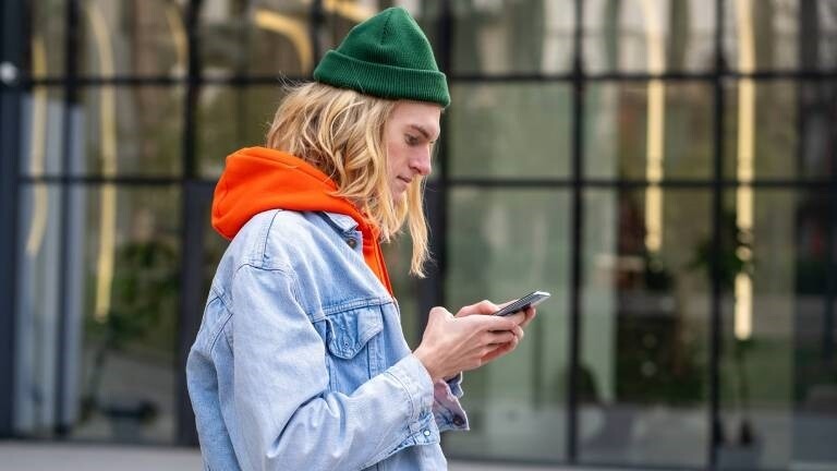 Ein junger Mann schaut auf den Bildschirm eines Smartphones