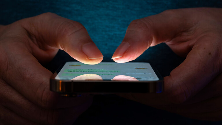 Frau tippt auf einem Apple iPhone13 Smartphone-Screen SMS.