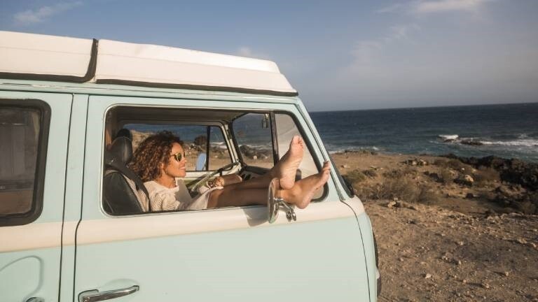 Eine Frau sitzt in einem Van und schaut auf das Meer
