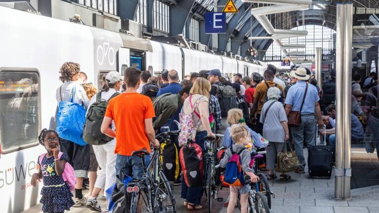 Menschenmasse versucht mit Gepäck und Rädern in einen Zug zu kommen (Bahnsteig im Hauptbahnhof Karlsruhe, 12.6.2025)