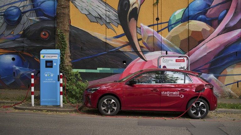 Ein E-Audto lädt an einer Ladestation. Im Hintergrund ein Graffiti mit einem Flamingo