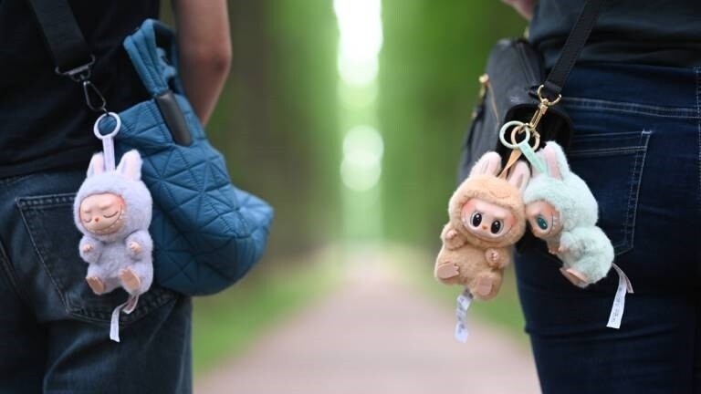 Zwei Personen tragen die Labubu-Plüschmonster an ihren Handtaschen