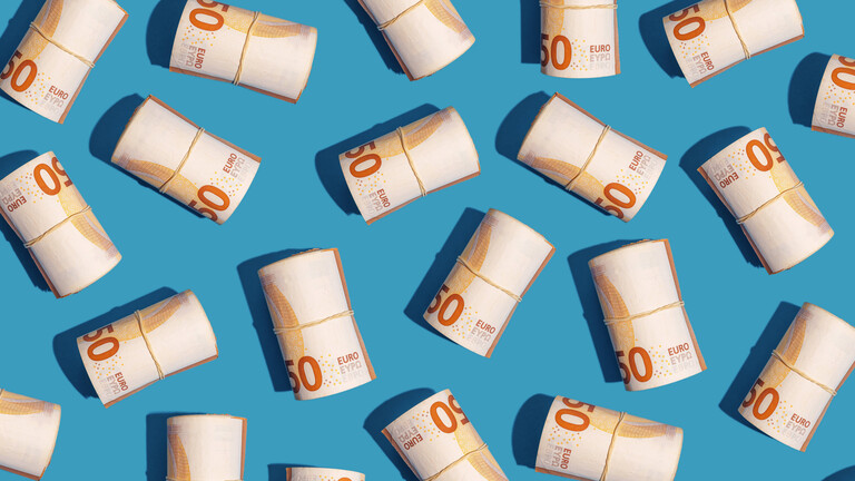 Rollen von Fünfzig-Euro-Scheinen auf blauem Hintergrund