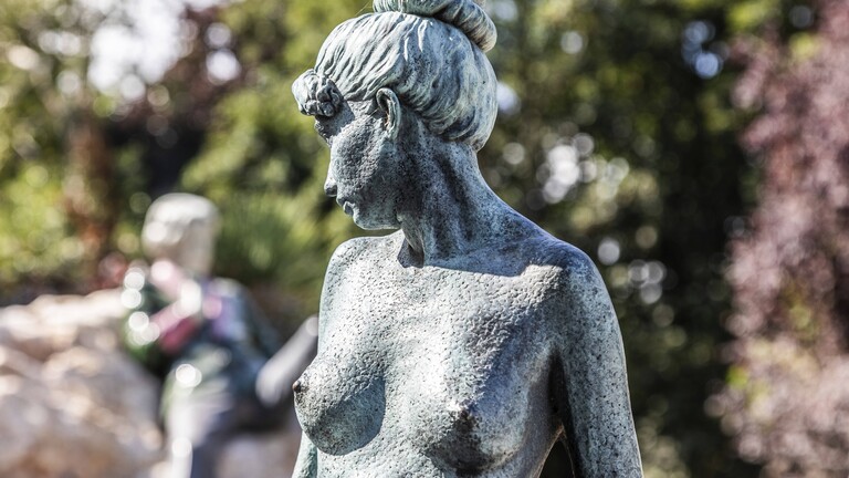 Bronzeskulptur einer nackten Frau, hinten Denkmal von Oscar Wilde, irischer Schriftsteller und Dichter, Merrion Square Park, Dublin, Irland