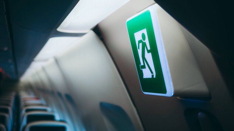 Schild weist zum Notusgang im Flugzeug