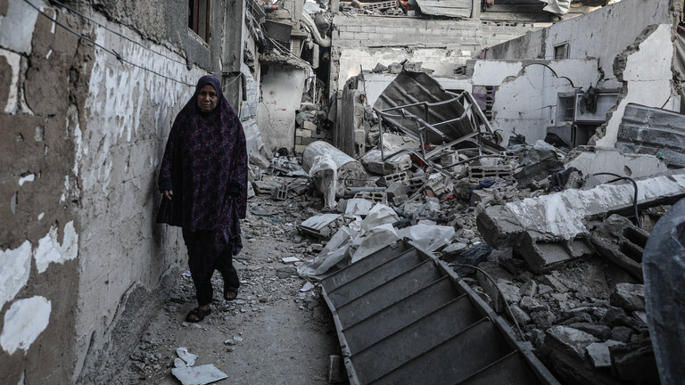 Eine Frau geht durch Trümmer im Gazagebiet