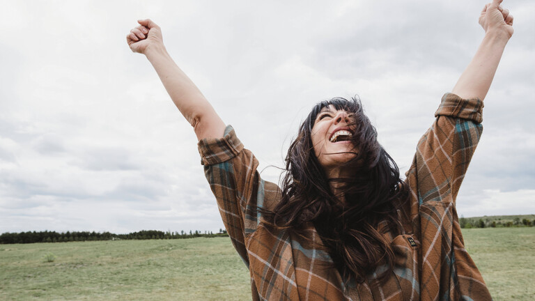 Eine Frau freut sich überschwenglich und reißt dabei die Arme in die Luft